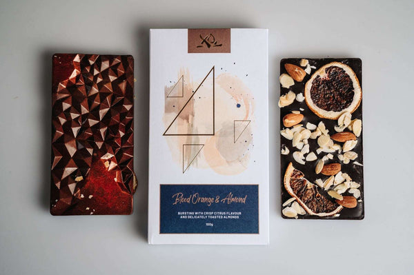 multiple dark chocolate bars with packaging, chocolate bars containing nuts and orange